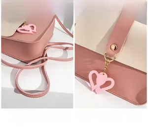 Detail der rosa-beigen Umhängetasche mit Herzanhänger und robustem Schultergurt