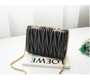 Close-up of black matelassé pleated leather bag with gold chain strap on a magazine