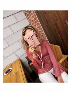 Détail d'un sac téléphone en cuir rose avec anneau métallique doré et gland décoratif