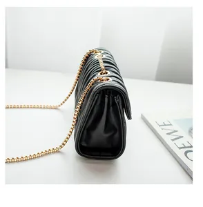 Detail of black quilted leather shoulder bag with gold chain strap and metal rings