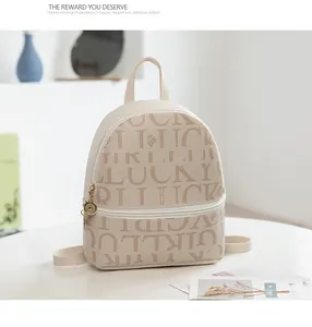 Detalle de mini mochila de cuero PU crema con estampados Lucky Girl y dije de cremallera