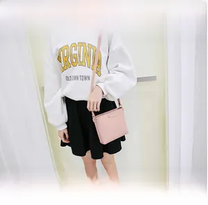 Mini soft pink crossbody bag shown on a model with a casual white sweatshirt