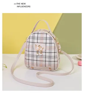 Detail of plaid patterned crossbody bag featuring pearl cat charms and gold stud accents