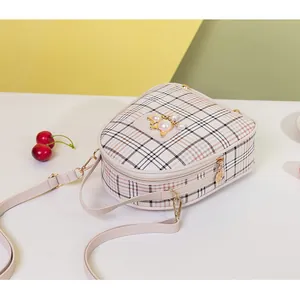 Detailed view of plaid crossbody bag featuring a golden fox and pearl embellishment