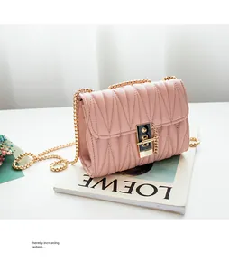 Close-up of pink quilted leather crossbody bag with gold chain strap and square metal lock