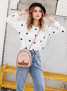 Foto estilo callejero de un mini bolso bandolera rosa y marrón con detalle de lazo