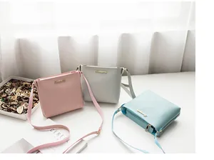 Three elegant leather mini crossbody bags in pink, grey and blue with golden logos