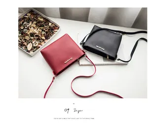 Detailed close-up of red and black leather crossbody bags with gold logo on white surface