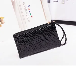 Detail of black crocodile texture clutch with gold zipper and wrist strap