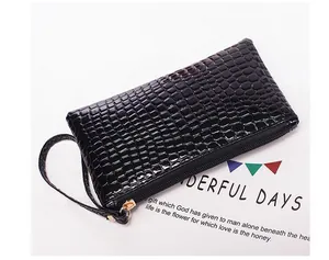 Detail of black crocodile embossed clutch bag with metal zipper and wristlet strap