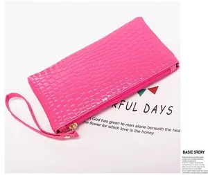 Detail of bright pink crocodile embossed texture on clutch bag with golden zipper