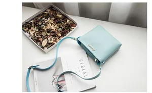 Side view of light blue mini crossbody bag with gold zipper and cursive metal lettering