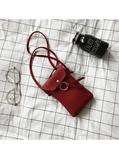 Détail du sac de téléphone en cuir rouge foncé avec anneau métallique et noeud