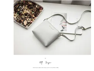 Close-up of minimalist light gray crossbody bag with gold logo on a stylist background
