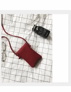 Vue détaillée du mini sac bandoulière en cuir rouge à motif litchi sur fond quadrillé