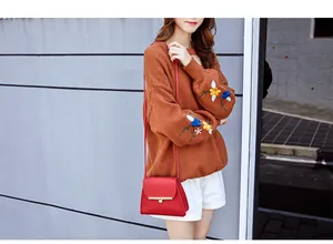 Close-up of red leather crossbody bag with gold metal buckle and thin shoulder strap