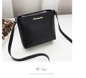 Close-up of black leather crossbody bucket bag with gold cursive logo and slim strap