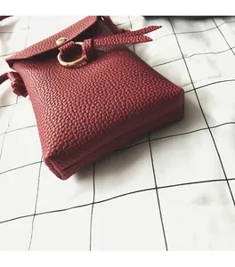 Détail du mini sac rouge en cuir litchi avec boucle dorée et fermeture à rabat aimanté