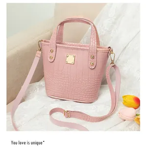 Dettaglio borsa a secchiello rosa coccodrillo con accenti dorati e decoro di tulipani