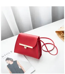 Detail of red crossbody mini bag featuring a sleek golden metal lock and smooth leather texture