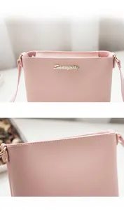 Close-up of pink synthetic leather crossbody bag featuring gold logo and precise stitching