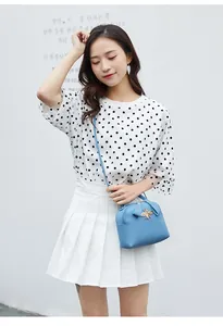 Outdoor shot of light blue litchi leather crossbody bag with gold bee buckle on model