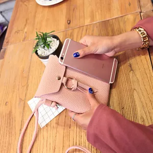 Mini sac bandoulière rose en cuir grainé avec anneau en métal sur une table en bois