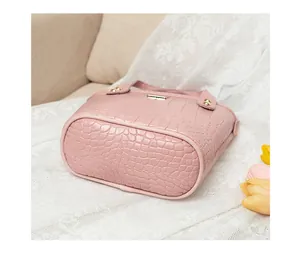 Dettaglio della borsa a secchiello rosa a motivo coccodrillo con eleganti fibbie dorate