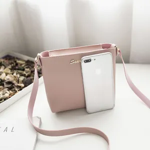 Minimalist pink faux leather crossbody bag shown next to a smartphone for size reference