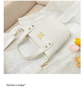 Dettaglio della borsa bianca motivo coccodrillo con elegante fibbia decorativa in metallo oro