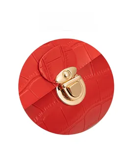 Close-up of golden metal clasp lock on red crocodile pattern leather handbag