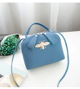 Detail of light blue lychee pattern leather bag with golden bee hardware and dual zippers