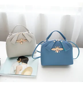 Litchi pattern crossbody bag detail featuring golden bee and bow accessories
