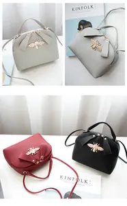 Detail of bee emblem and bow design on lychee pattern mini crossbody bags in three colors