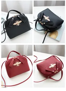 Detail of bee metallic emblem on litchi texture mini leather bag in two colors