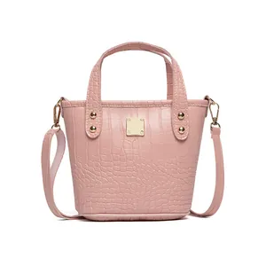 Elegante borsa a secchiello rosa coccodrillo con decoro in metallo e manici su sfondo bianco