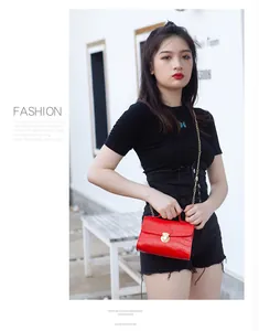 Detail of red crocodile pattern handbag with gold clasp and chain on a stylish model
