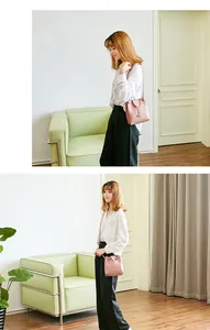 Detail van roze emmer tas met metalen hert hanger en smalle schouderband gedragen door model