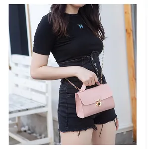 Detail of pink croc-effect mini bag featuring golden twist-lock and chain strap on a model