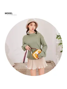 Chic yellow and white crossbody bag with striped strap shown on a green knit outfit