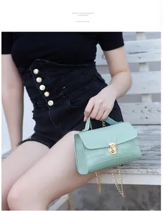Detail view of mint green faux crocodile leather bag with golden twist lock and chain strap