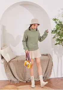 Chic yellow leather crossbody bag with striped ribbon strap on green knit sweater