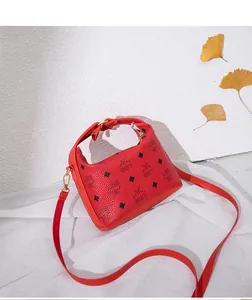Dettaglio della piccola borsa rossa in pelle martellata con stampa e fibbie dorate