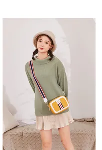 Detail of yellow camera bag with tricolor ribbon strap and gold hardware on model