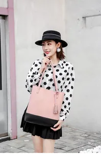 Detailansicht der pink-schwarzen Totebag mit Quasten, gehalten von einem Model in Freizeitmode