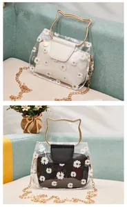 Detail of transparent PVC crossbody bag with daisy print and golden cat-ear metal handles