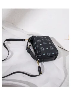 Dettaglio della trama in finta pelle nera e hardware dorato della piccola borsa quadra