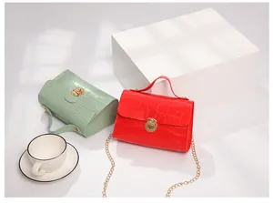 Detail of red and mint green faux crocodile leather bags with gold chain straps and metal locks