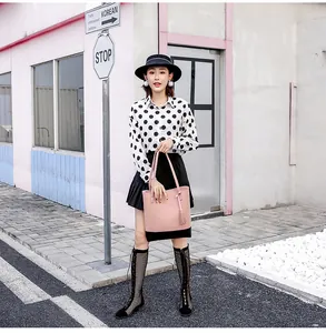 Detail einer Tasche in Kontrastfarben Pink und Schwarz mit Quaste von Model getragen