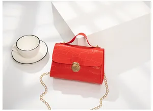 Detail of red crocodile texture small square bag with golden chain and clasp closure
